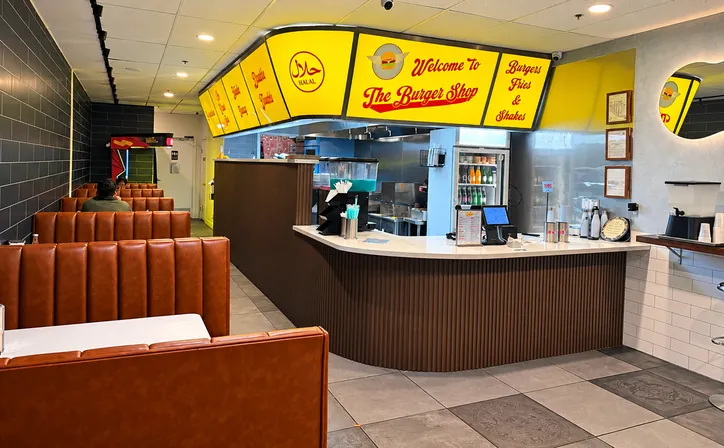 Tan leather booths in the dining room, beside the front counter and its yellow signs